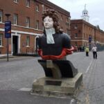 Figurehead of HMS Benbow, with some of the fine Georgian naval buildings beyond